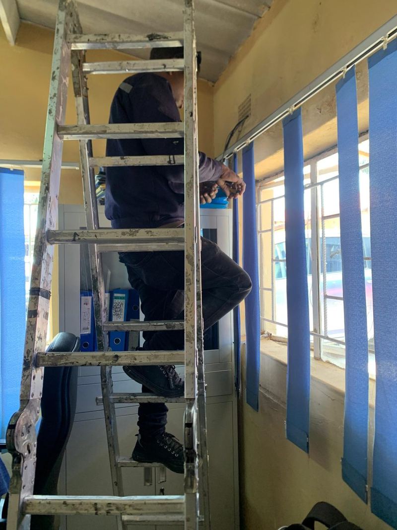 Technician on a ladder routing network cable through the ceiling