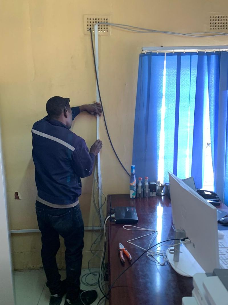 Technician installing wall trunking for office data cabling